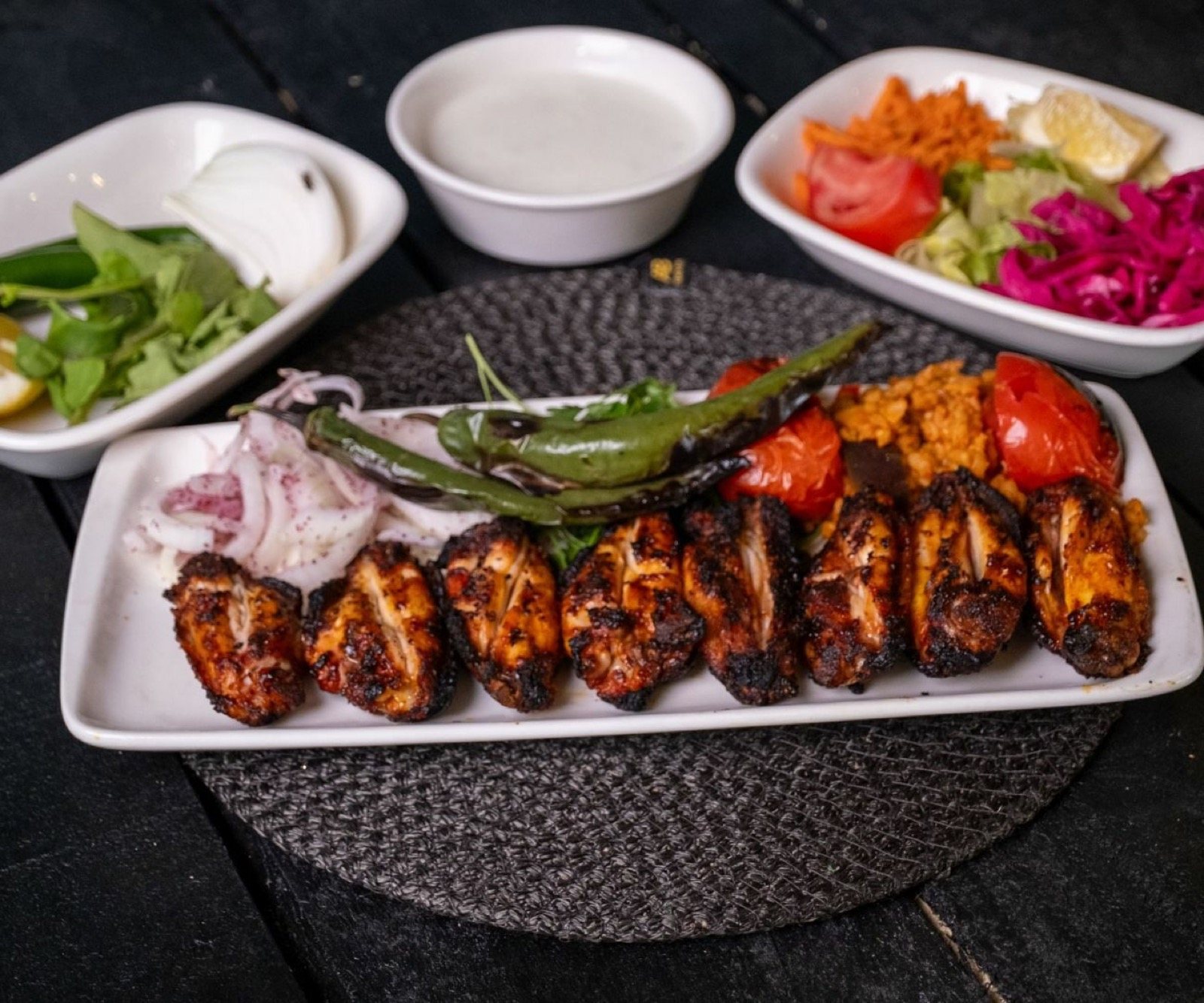 Uzun tabakta közlenmiş tavuk kanat, bulgur pilavı, sumaklı soğan, yanında salata ve yoğurt